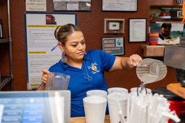 A girl pouring water in glasses at a cafe