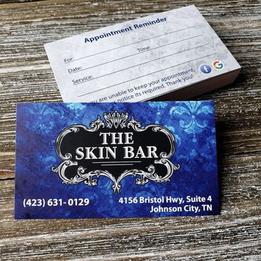 The Skin Bar appointment reminder business cards on a wood background