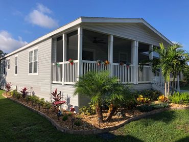 house with landscaped bed around front and side containing rock, pavers, trees, and plants