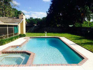 backyard of a home with a pool and green sod around backyard
