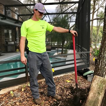 person standing holding a shovel, digging a hole