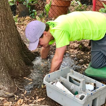person elbow-deep in water, servicing an irrigation system