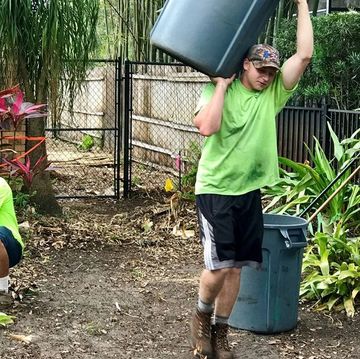 person carrying trash can of debris overhead
