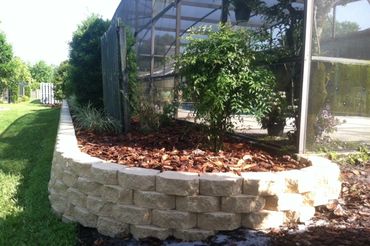 retaining wall behind a pool with mulch and plants