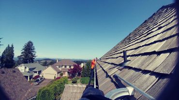 Worker cleaning gutters on a rooftop in a suburban neighborhood.