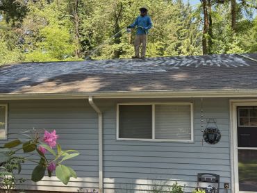 Person spraying roof on a sunny day.