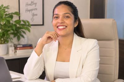 Smiling woman in white blazer at office desk.