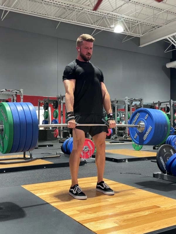 Man lifting heavy barbell in gym, focused on strength training.