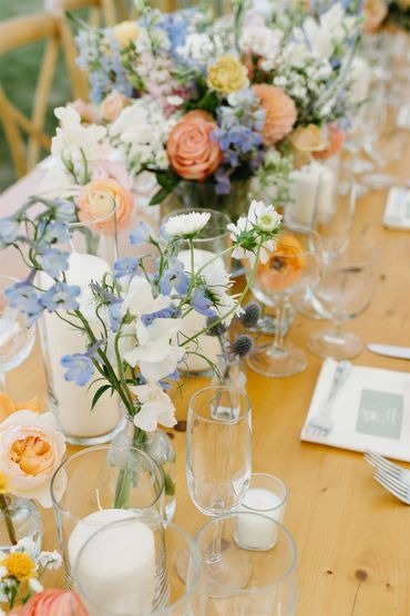 Farmhouse table with flowers in colors of peach, orange, light blue, pink and white. 