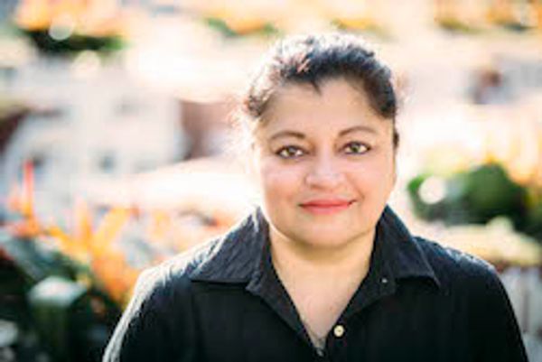 Smiling woman in a black shirt outdoors.