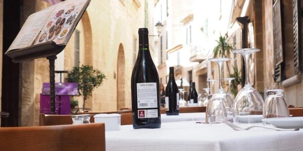 Outdoor restaurant table with wine bottles and glasses.