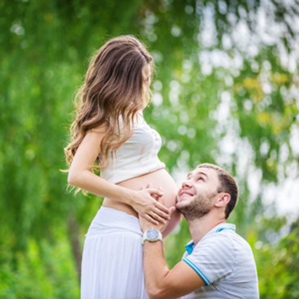 Man cherishing pregnant woman's belly outdoors.