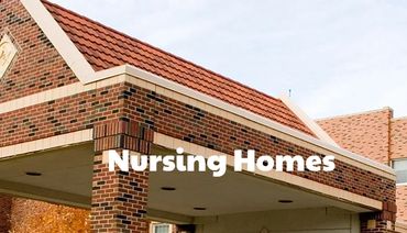 Exterior view of a brick nursing home with benches and trees.