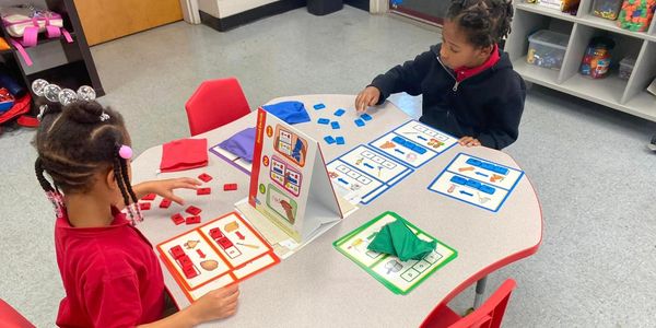 Two children engaged in a colorful educational activity at a table.