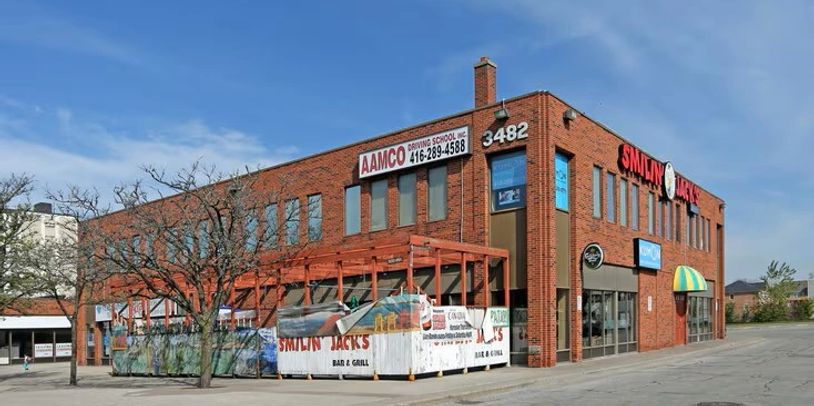 Brick building housing Smilin Jack's Bar & Grill and AAMCO Driving School.