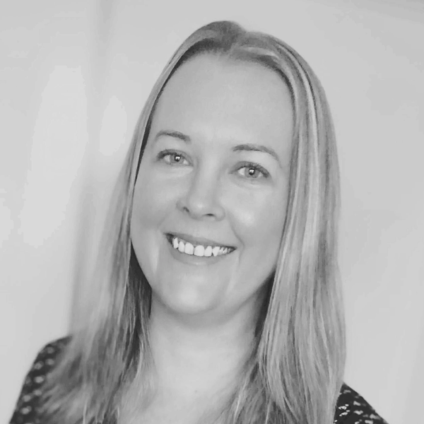 Black and white image of a woman with light straight hair, smiling friendly.