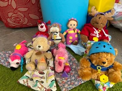 A collection of colorful stuffed animals and dolls arranged on fabric pieces.
