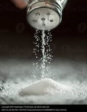 Salt Flowing freely from a shaker onto a surface.