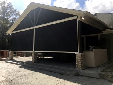 Motorized roll shades on a gazebo with a transom at top with fixed screens.