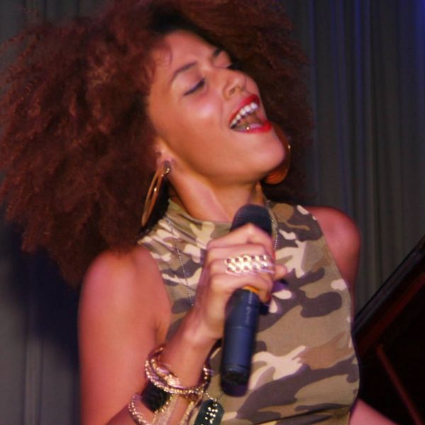 A woman passionately singing into a microphone on stage.