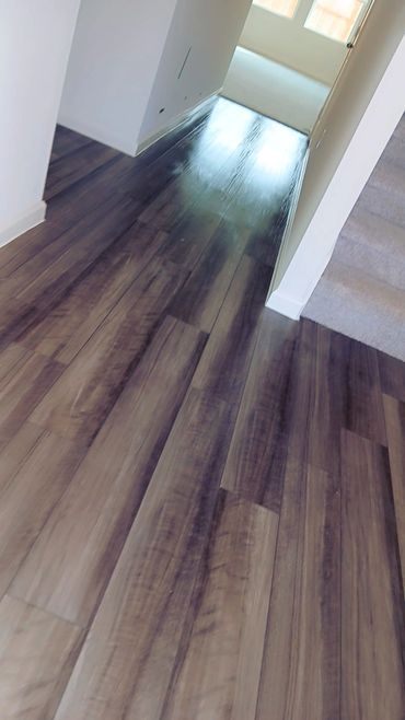 Polished dark wood floor in a hallway with carpeted stairs.