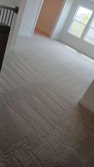 Bright empty room with freshly vacuumed carpet and large windows.