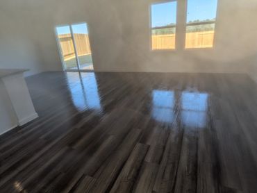 Empty room with shiny dark wooden floor reflecting windows.