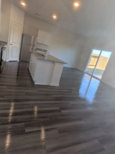 Modern kitchen with island, stainless steel appliances, and wood-look flooring.