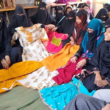 Women in traditional attire displaying colorful garments together.