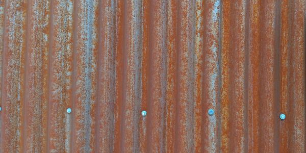 Rusty corrugated metal sheet with visible screws.