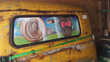 A couple rides down a dirt road in the cab of this old truck/bar!