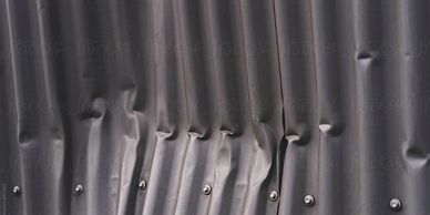 dented metal panesl on building