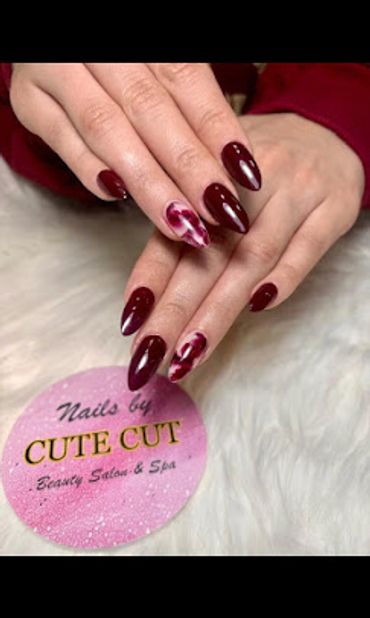 .Professional burgundy nails with marble accent design at Cute Cut Beauty Salon & Spa