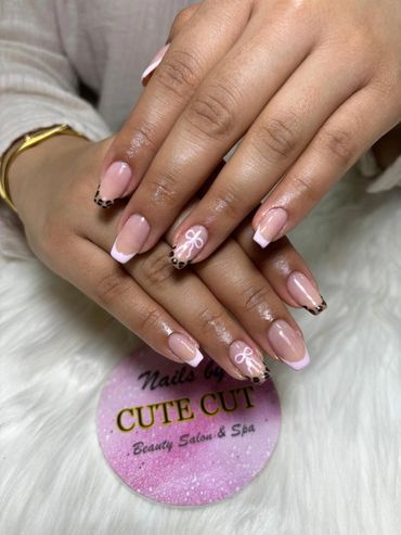 Elegant nails with pink tips, leopard prints, and white bow designs.