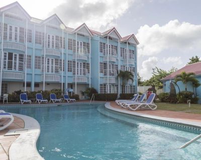Outdoor pool with lounge chairs next to a blue building.