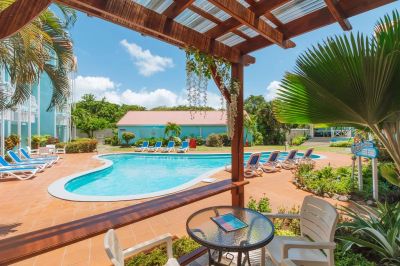 Outdoor pool area with lounge chairs and a shaded seating spot.