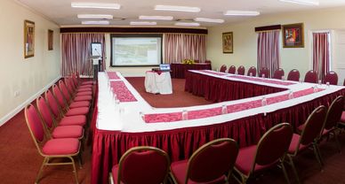Conference room set up with red chairs and U-shaped tables.