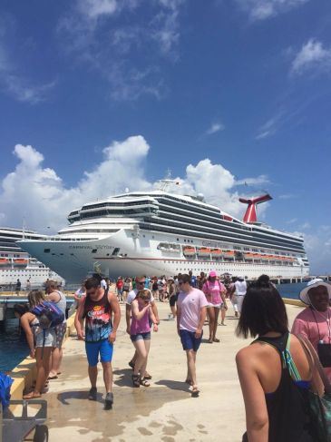 People walking on pier near Carnival Victory cruise ship.