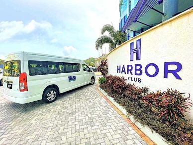 White shuttle van parked outside Harbor Club.