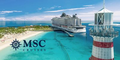 MSC Cruises ship docked at a tropical island with lighthouse.
