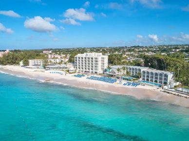 Beachfront hotel with blue chairs and clear water.