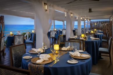 Elegant seaside restaurant with blue tablecloths and candlelight.