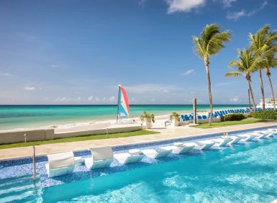 Beachside pool with ocean view and palm trees.