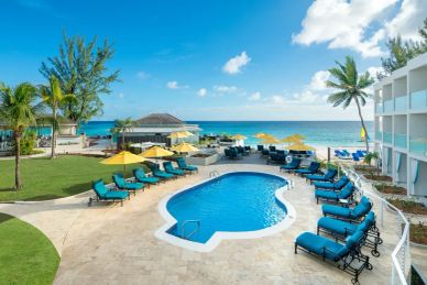 Beach resort pool with blue loungers and yellow umbrellas.