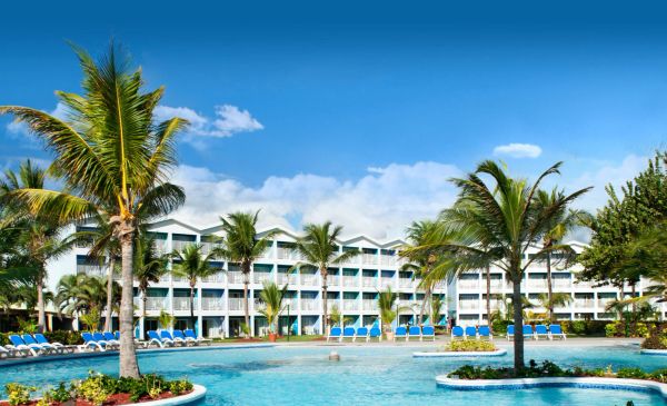 Resort pool area with palm trees and lounge chairs.