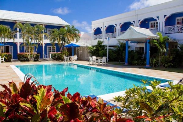 Resort pool area with colorful plants and blue sky.