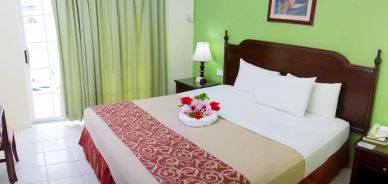 Cozy hotel room with a decorated bed and green walls.