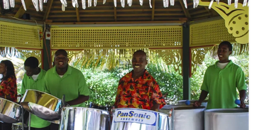 Group playing steel drums under a hut.