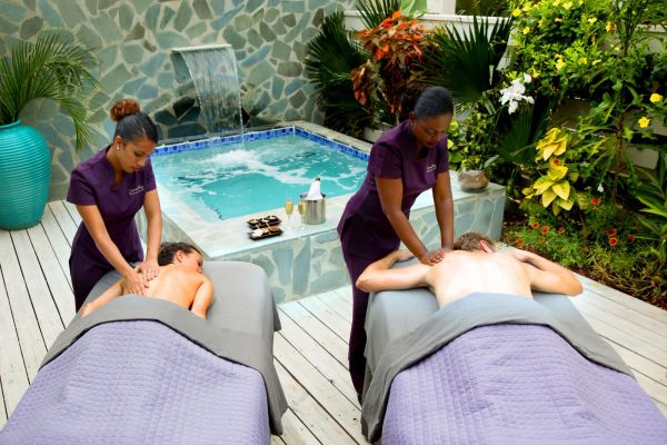 Couple getting massages near a pool in a garden.