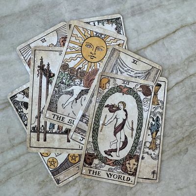 A scattered deck of vintage tarot cards on a marble surface.